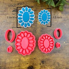 three flower shaped cookie cutters on top of a wooden table next to potted plants