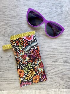 a pair of sunglasses sitting on top of a wooden table next to a wallet case