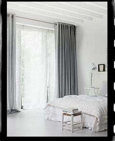 an image of a bedroom with white walls and curtains