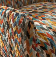 an upholstered couch with multicolored fabric on it's back and sides