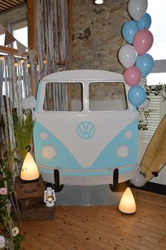 a blue and white vw bus with balloons on the back is parked in front of a stone wall