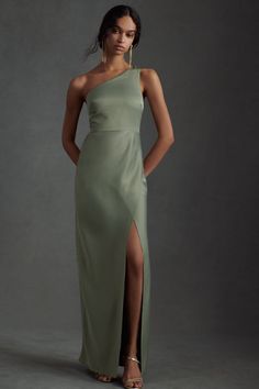 a woman in a long green dress with one leg slited out, posing for the camera