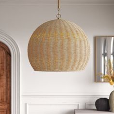 a room with white walls and a large rattan light fixture hanging from the ceiling