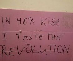 a pink wall with writing on it that says in her kiss i taste the revolution