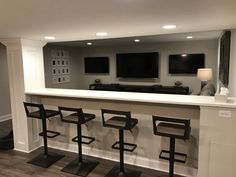 a bar with four stools in front of it and a television on the wall