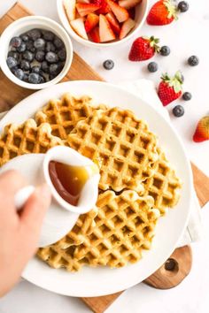 waffles with syrup being drizzled over them on a white plate