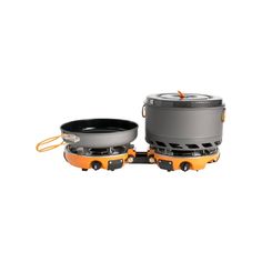 an orange and gray camping stove with two pots on the side, sitting next to each other