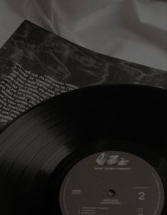 an old vinyl record sitting on top of a white sheet