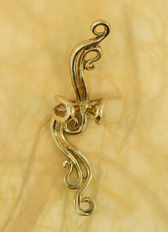 This French Twist Ear Cuff is cast in bronze and is elegant and fluid and can be worn on either the left or the right ear (diamond not included). Our ear cuffs require no piercings. Starting near the top of the ear, slide the ear cuff down along the edge of the ear's cartilage. You may gently open or close the opening of the ear cuff to accommodate the thickness of your ear. Our bronze ear cuffs are antiqued lightly, and bronze will tarnish, or patina over time. To maintain the golden color, cle Elegant Gold Metal Ear Climbers, Elegant Silver Brass Ear Cuff, Elegant Brass Ear Climbers As A Gift, Elegant Gold Brass Ear Cuff, Artistic Single Gold Earring, Gold Metal Ear Cuff For Wedding, Gold Metal Wire Wrapped Ear Cuff, Gold Wire Wrapped Ear Cuff As Gift, Elegant Pierced Brass Ear Cuff