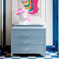 a blue dresser with a pink hat on top of it next to a white busturine