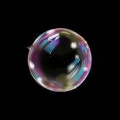 a soap bubble floating in the air on a black background