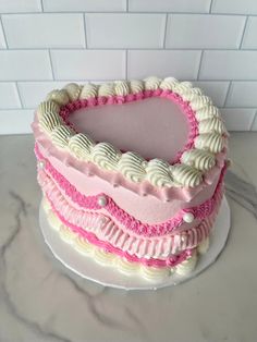 a heart shaped cake sitting on top of a white table next to a brick wall