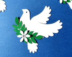 paper doves with green leaves and white flowers on a blue background that is cut out