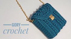 a blue crocheted purse sitting on top of a white table next to a chain