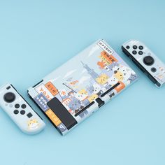 two nintendo wii controllers sitting next to each other on a blue surface with city scenes