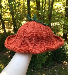 an orange crocheted hat on top of a white hand