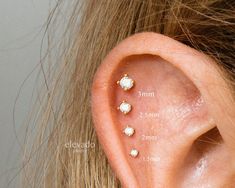 a woman's left ear with three small diamond studs on the top of it