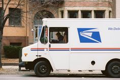 an postal truck is parked on the side of the street with its door open and people inside