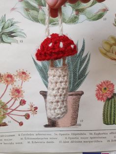 a hand holding a crocheted mushroom on top of a plant