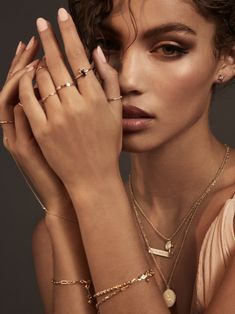 a woman with her hands on her face wearing rings and bracelets, posing for the camera