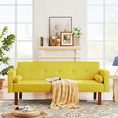 a living room with a yellow couch and potted plants on the floor next to it