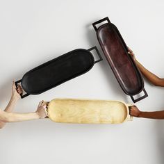 three people holding wooden objects in the shape of a skateboard and a rolling board