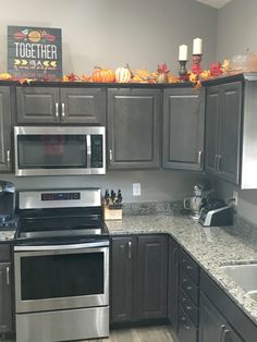 a kitchen with stainless steel appliances and granite counter tops is pictured in this image, there are pumpkins on top of the cabinets