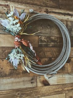 a wreath made out of rope and flowers on top of a wooden wall with the words,