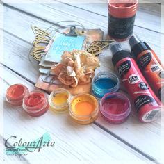 several different colors of paint sitting on top of a white wooden table next to each other