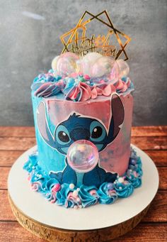 a blue and pink birthday cake with an elephant on the top, surrounded by bubbles