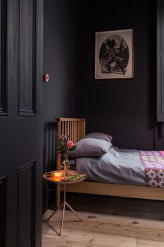 a bed sitting in a bedroom next to a table with flowers on top of it