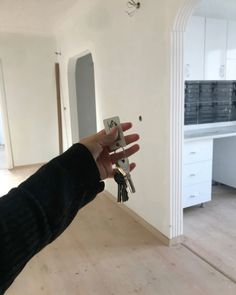 a person holding keys in front of a white room with an arch and kitchen behind them