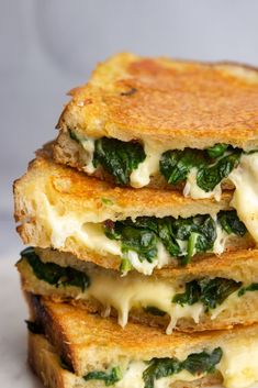 three grilled cheese and spinach sandwiches stacked on top of each other