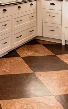 a kitchen with black and white checkered flooring, cabinets and counter tops is shown