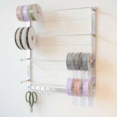 a white wall mounted shelf with several spools of thread on it