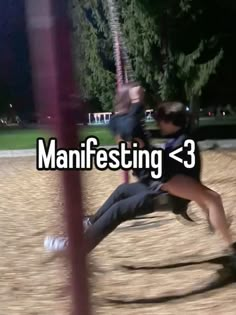 a man and woman are sitting on a swing in the park, text reads manifesting = 3