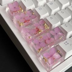 pink and gold butterflies are placed in clear boxes on a white computer keyboard with keys