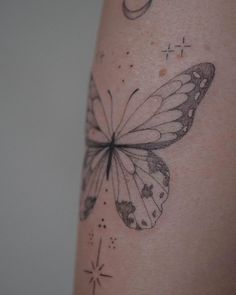 a close up of a butterfly on the back of a woman's arm with stars