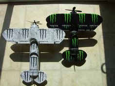 two remote controlled airplanes with monster logos on the front and back sides, one is black and green