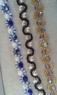 four different types of beaded bracelets on a white cloth with black and blue beads