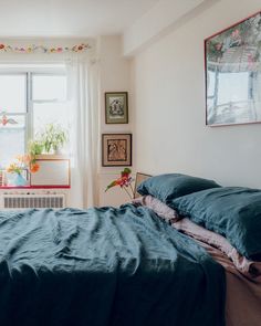 a bed sitting in a bedroom next to a window with pictures on the wall above it