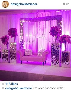 a couch sitting on top of a stage next to a mirror and flower vases