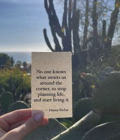 someone holding up a piece of paper with a quote on it in front of some cacti