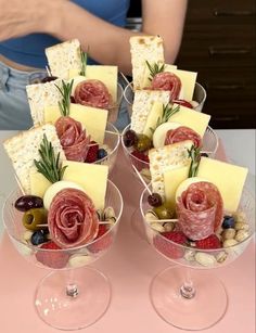 two wine glasses filled with different types of cheese and meats on top of each other