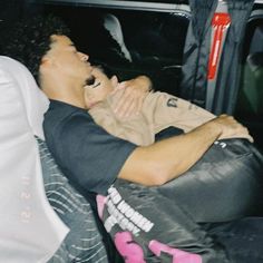 a man laying in the back of a car with his head on someone's chest