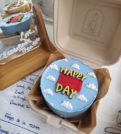 a birthday cake with the words happy day in blue icing and clouds on it