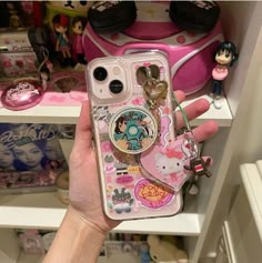 someone is holding up their phone case with some stickers on it, and there are other items in the background