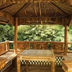 a wooden gazebo with benches and tables in the shade on a deck overlooking trees