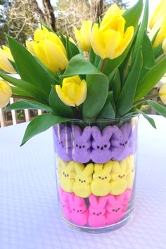 a vase filled with lots of yellow and purple peeppies sitting on top of a table