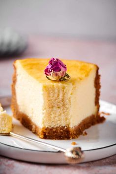 a piece of cheesecake on a white plate with a pink flower in the middle